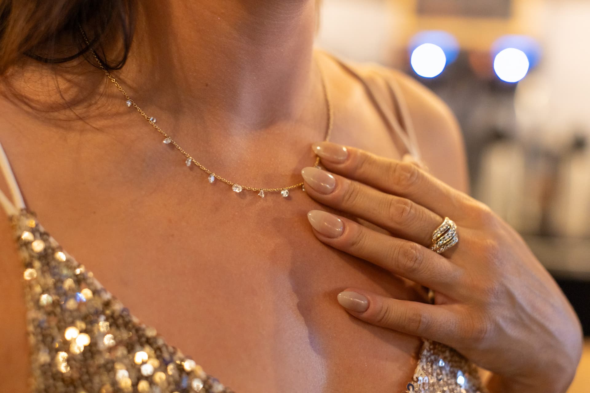Gold necklace with small diamond drops paired with a diamond ring on an elegant evening outfit
