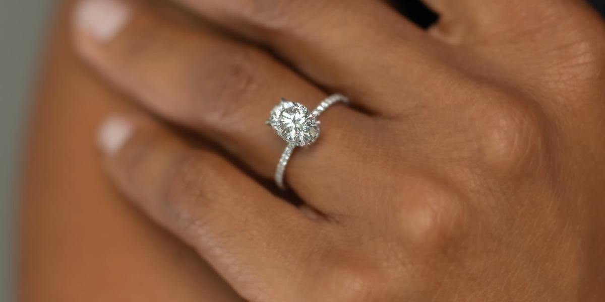 Close-up of a round diamond engagement ring on a white gold band worn on hand