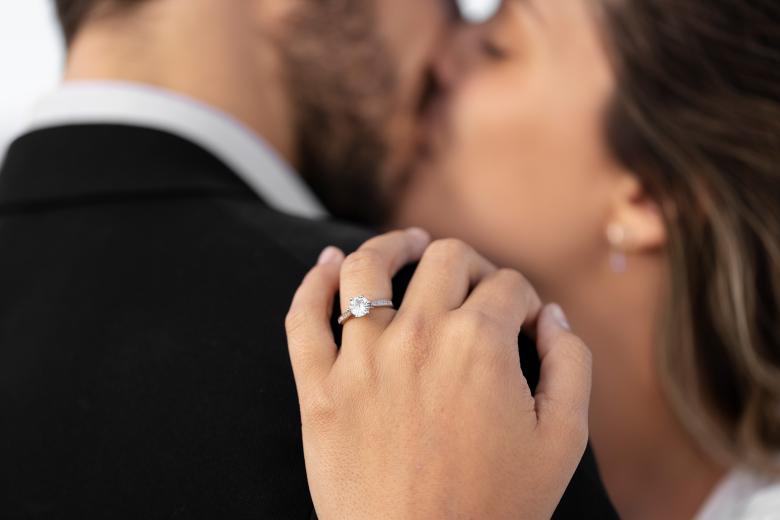 Couple kissing while hand wearing ring in focus