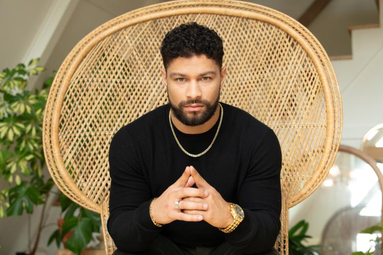 Man sitting in a chair wearing a tuscany gold chain. 