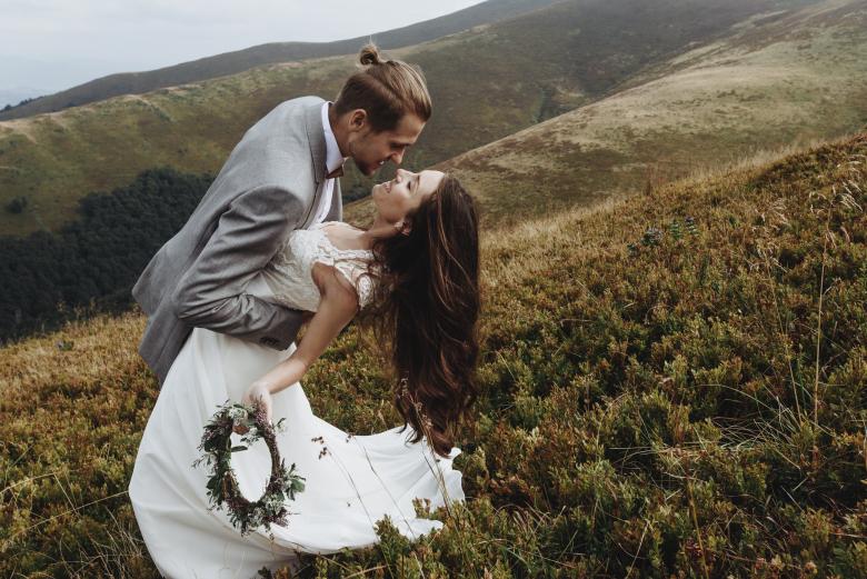 Groom dance dipping bride before kissing on a mountain background
