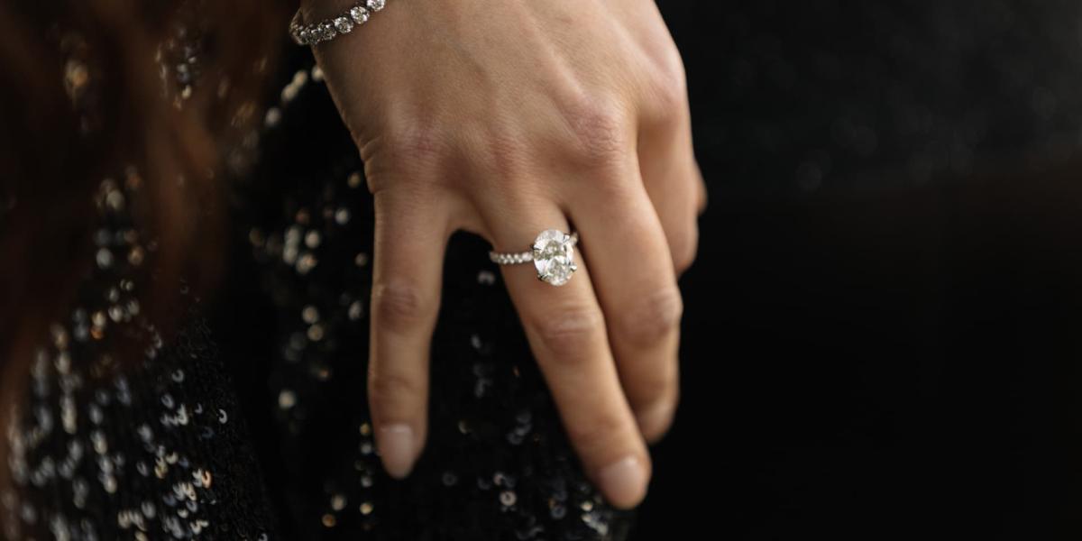 Oval diamond engagement ring on a hand with a diamond bracelet